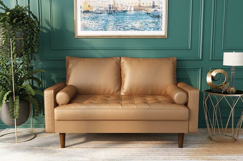 A green living room wall with a brown leather couch and a painting of water 