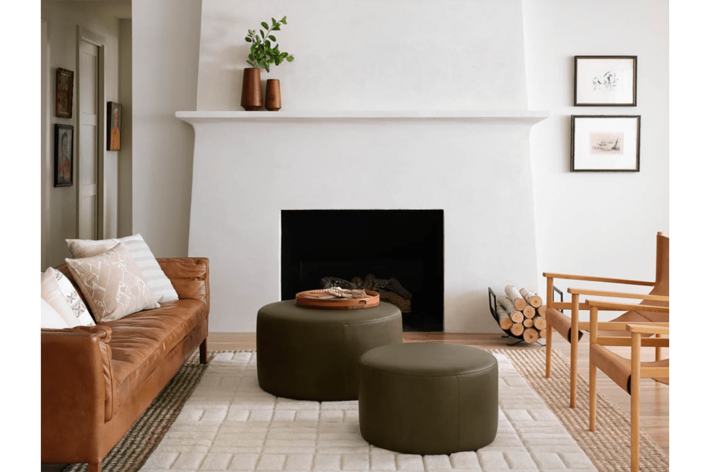 A white living room with green ottomans in the center of the room with chairs and a brown coach on either side 