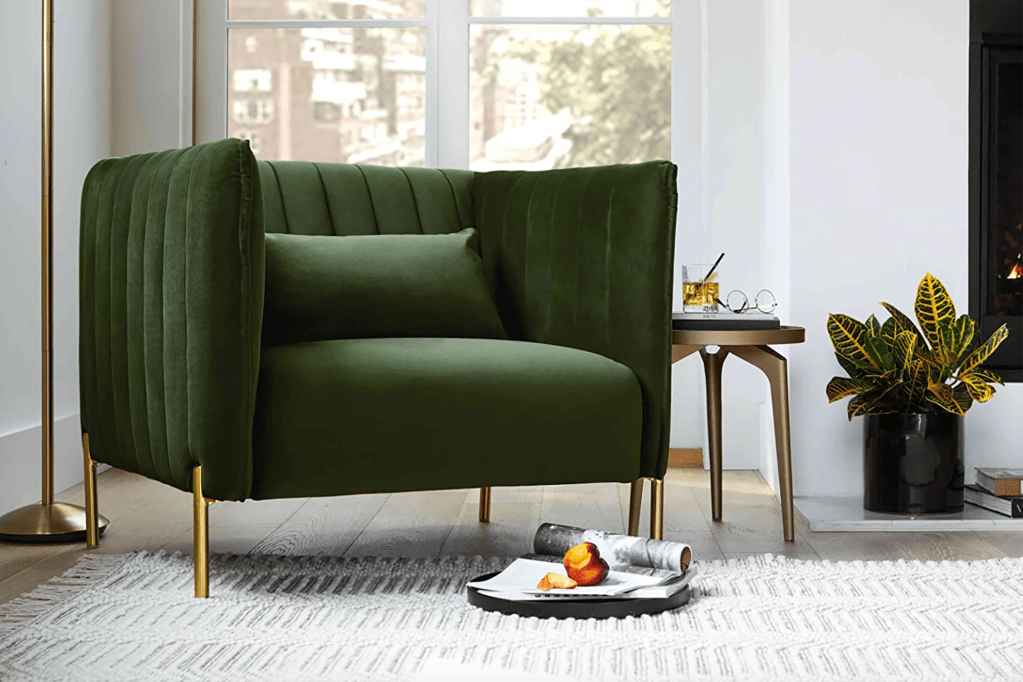 A green couch chair in a living room with a gray rug 