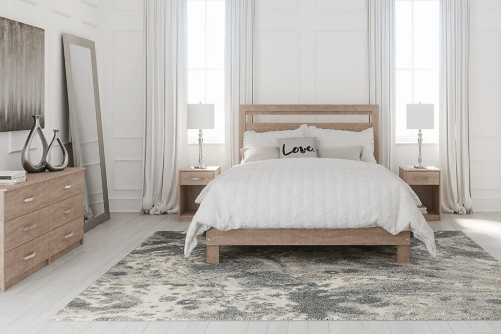 A white bedroom with a bed on a gray rug 